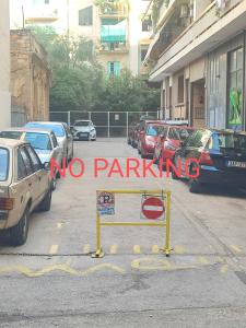 um sinal de não estacionar num parque de estacionamento com carros estacionados em Apartment Dimitris em Atenas