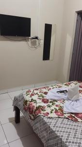 Cama en habitación con TV en la pared en Pousada Vidal en Carolina