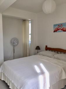a bedroom with a white bed and a fan at La Péninsule Town Apartment Curepipe No 4 in Curepipe