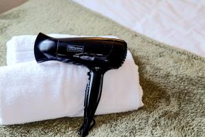 a black blow dryer sitting on top of a pile of towels at Emerald House - Prime Location - Free Parking, Pool Table, Fast Wifi and Sky TV by Yoko Property in Milton Keynes