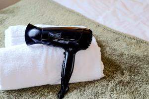 a black blow dryer sitting on top of a pile of towels at The Cosy House in Central MK with Free Parking, Pool Table, Fast Wifi, Smart TV and Garden by Yoko Property in Milton Keynes