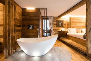 a bathroom with a large tub and a bed at Revivre Village Adults only in Champorcher