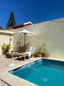 a swimming pool with an umbrella and a table and chairs at Beach house upscale villa with pool in Costa da Caparica