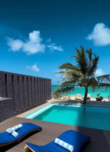 a swimming pool with a palm tree and the ocean at Clarks Exotica, Kamadhoo Maldives in Baa Atoll