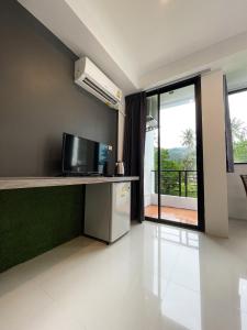 a room with a kitchen with a television and a balcony at Kefir Phuket in Kamala Beach