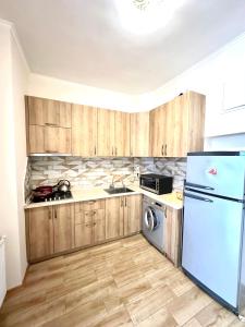 Una cocina con gabinetes de madera y refrigerador. en Studio Flat in Center of Tbilisi, en Tiflis