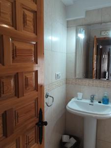 uma casa de banho com um lavatório, um espelho e uma porta em LA SOLANA em Valdemoro-Sierra