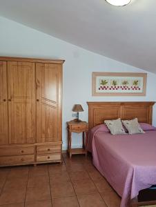 1 dormitorio con cama morada y armario de madera en LA SOLANA, en Valdemoro-Sierra