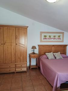 a bedroom with a purple bed and a wooden cabinet at LA SOLANA in Valdemoro-Sierra +44 photos