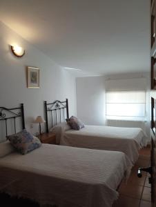 1 dormitorio con 2 camas y ventana en LA SOLANA, en Valdemoro-Sierra