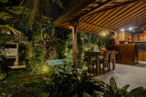 Moringa Ubud Villa في أوبود: فناء في الهواء الطلق مع طاولة وكراسي تحت البرغولية