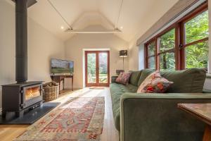 sala de estar con sofá verde y chimenea en Weavers Mark Cottage, en Diss