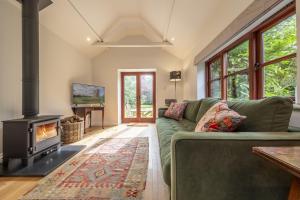 a living room with a green couch and a fireplace at Weavers Mark Cottage in Diss