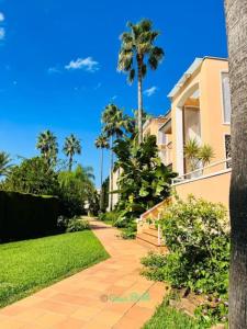 a walkway in front of a house with palm trees at Casa Brût - OLIVA NOVA in Oliva