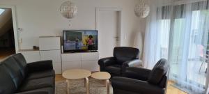 a living room with two black chairs and a tv at TOP Apartments Kaiserebersdorf in Vienna