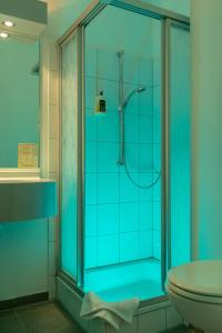 a blue bathroom with a shower and a toilet at Montana Hotel Senden in Senden