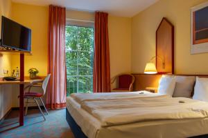 a hotel room with a bed and a desk and a window at Montana Hotel Senden in Senden