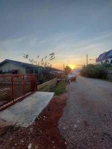 Eine Straße mit einem Zaun und dem Sonnenuntergang im Hintergrund in der Unterkunft Segamat Tunas Homestay in Segamat