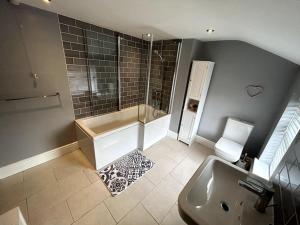 a bathroom with a shower and a tub and a sink at Two Bed Charming Cottage in Crewe