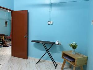 Zimmer mit einem Tisch und einer blauen Wand in der Unterkunft Segamat Tunas Homestay in Segamat
