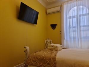 um quarto com uma cama e uma televisão na parede em Casinhas no Carolina - Hostel em Porto