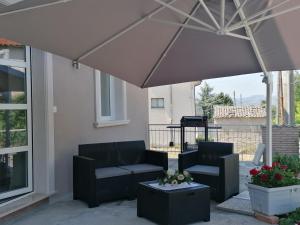 un patio con 2 sillas y una sombrilla en B&b Villa Elena - Irpinia, en Mirabella Eclano