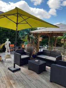 a yellow umbrella on a deck with chairs and a table at Les vignobles du Bordelais in Montussan