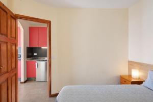 1 dormitorio con 1 cama y cocina con armarios rojos en Moijama 10, en Los Llanos de Aridane