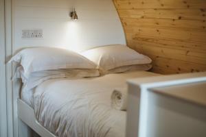 un letto con lenzuola e cuscini bianchi in una stanza di Carlton Manor Pods ad Aldbrough