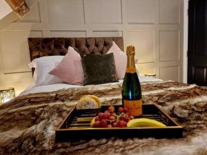 a tray of fruit and a bottle of champagne on a bed at Hamilton-The Cruck Luxury Let in Scorton