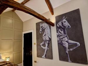 two paintings of horses on the wall of a bedroom at Hamilton-The Cruck Luxury Let in Scorton