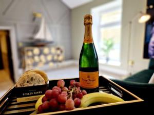 a bottle of champagne next to a tray of fruit at Hamilton-The Cruck Luxury Let in Scorton