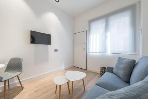 uma sala de estar com um sofá azul e uma mesa em JES Apartment A Nuevos Ministerios em Madri