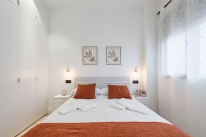um quarto branco com uma cama grande com almofadas laranja em JES Apartment A Nuevos Ministerios em Madri