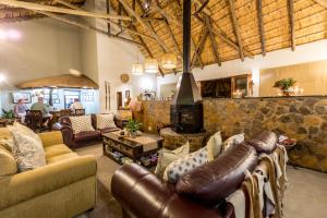 a living room with leather furniture and a stone wall at Elephant Rock Private Safari Lodge in Ladysmith
