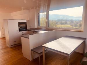 eine weiße Küche mit einem Tisch und einem großen Fenster in der Unterkunft Obstbau Apartment am See in Lindau