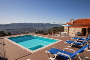 a swimming pool with chairs next to a house at Emily's House in Arcos de Valdevez