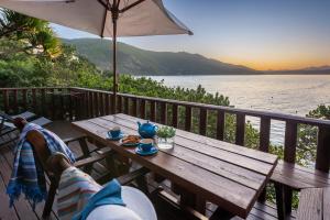 uma mesa de madeira sentada num deque com vista para a água em Under Milkwood Resort em Knysna