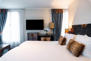 a bedroom with a large white bed and a television at Pavillon Opéra Grands Boulevards in Paris