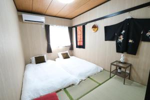 Una pequeña habitación con una cama y una ventana. en Housegreen, en Tokio