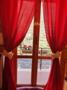 uma janela com cortinas vermelhas e vista para uma varanda em La Piccola Baita di Filettino em Filettino