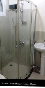 a shower with a glass door next to a sink at My Quiet Place at The Beacon - Makati City in Manila