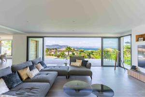 un salon avec un canapé et une table en verre dans l'établissement Villa Palma Giens - Vue Mer Panoramique -Piscine Chauffée Mai à Septembre- 4 chambres -Garage, à Hyères