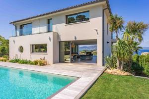 une maison avec une piscine en face de celle-ci dans l'établissement Villa Palma Giens - Vue Mer Panoramique -Piscine Chauffée Avril à Septembre- 4 chambres -Garage, à Hyères