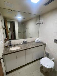 ein Badezimmer mit einem Waschbecken, einem WC und einem Spiegel in der Unterkunft Ondina Apart Hotel - Apto 419 in Salvador