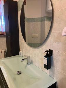 ein Badezimmer mit einem Waschbecken mit einem Spiegel und einem Seifenspender in der Unterkunft CV Martesana Gorgonzola 4 in Gorgonzola