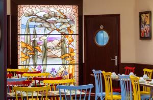 une salle à manger avec des chaises colorées et un vitrail dans l'établissement Hotel Terminus Montparnasse, à Paris