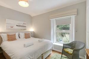 a bedroom with a large white bed and a window at Lilac Cottage in Parkend