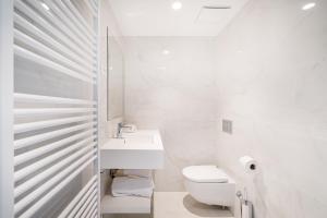 uma casa de banho branca com um lavatório e um WC em Miramare Hotel em Zadar