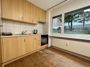 a kitchen with wooden cabinets and a large window at Alpine Retreat: 4-Person Apartment near Zermatt in Täsch